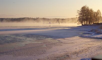 Delightful evening winter landscape.
Frozen lake covered with fog and sunset evening light.