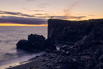man on top of the hill in a sunset on the west coast of iceland
