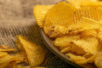 Fluted potato chips on a background of homespun fabric with a rough texture. Close up.