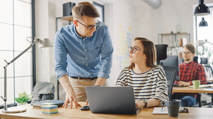 Young Casual Business Couple are Using Laptop in Creative Agency Loft. Friendly Easygoing Coworking...