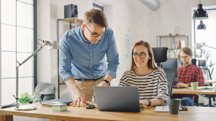 Young Casual Business Couple are Using Laptop in Creative Agency Loft. Friendly Easygoing Coworking Atmosphere. They Discuss and Brainstorm Ideas. Manager Explaining New Work Strategy.