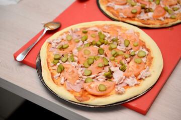 Dough piece for making pizza with smoked chicken and tomatoes, close-up.