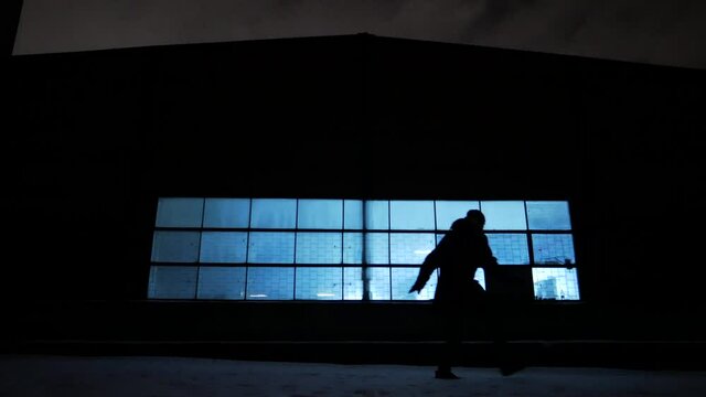 silhouette of a male thief going to steal in the night city