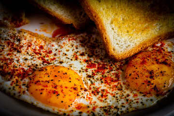 Fried eggs with toast.eggs fried with sunny side up and garnished with black pepper,red chilli powder and salt,with freshly made toasts 