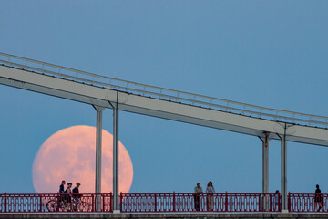 Silhouettes of people on the bridge against the background of the rising full moon, Kiev, Ukraine