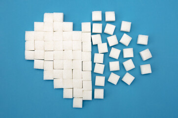 heart that splits into sugar cubes on a blue background close up, Top view. Concept of broken heart, health