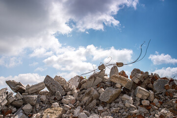 The wreckage of the remains of a building against a blue sky with gray clouds. Background