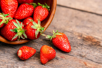 wooden bowl full of fresh strawberries on the brown table