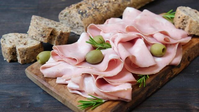 Italian mortadella traditional antipasti on a wooden plate, served with olives