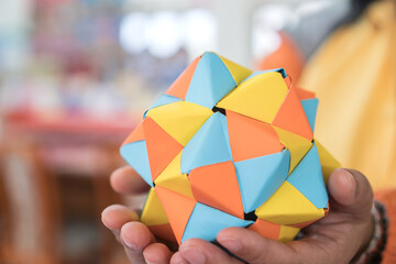 multicolor modular origami star sphericalal of modular origami spiky ball model on student hand,...