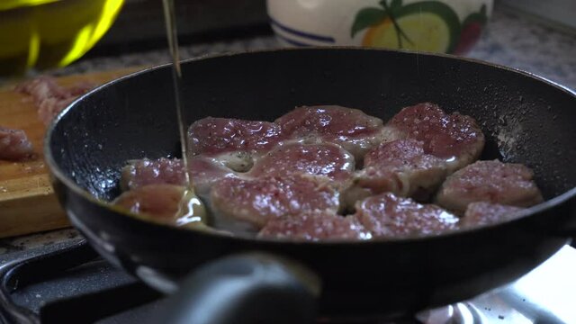 Aceite cayendo sobre filetes de solomillo en una sarten cocinando