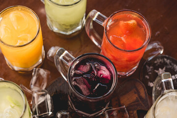 lemon, strawberry, kiwi, passion fruit caipirinhas, with ice spread over rustic table