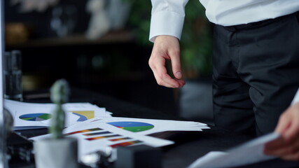 Businessman holding reports on paper in office. Entrepreneur standing at table