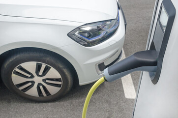 Modern electric car plugged in charging on the street station. New energy vehicles, environment...