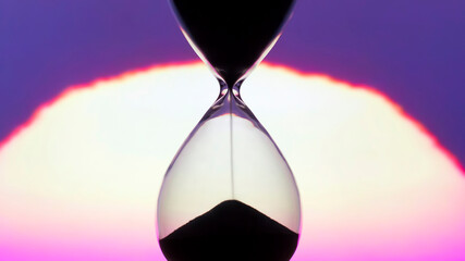 Hourglass on the background of a sunset. The value of time in life. time measuring tool. An...