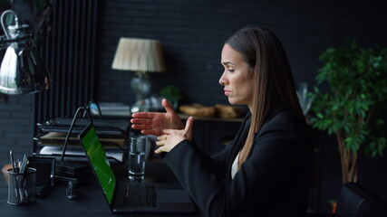 Successful businesswoman calling video online on laptop with green screen