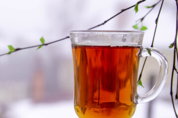 Tea in a transparent Cup against the background of spring foliage.