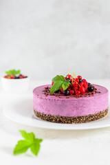 Mousse cashew cake with black currant and chocolate praline on a white plate. Sugar, lactose, gluten free. Vegan dessert, healthy food.