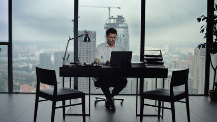Businessman working on laptop computer in office. Male worker using laptop