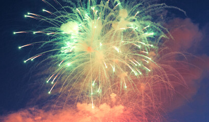 Fototapeta premium fireworks with green, yellow, red sparks in the night sky. Holidays, New Year, Christmas, Birthday, Wedding, Fire show, festive golden fireworks with sparkles on the blue sky. City day, holiday