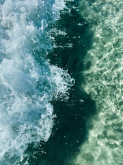 Small waves on the transparent clear water of the sea. White sea foam