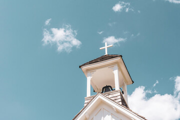 Bell tower of the church with a white cross, symbolizing Christianity and religion.