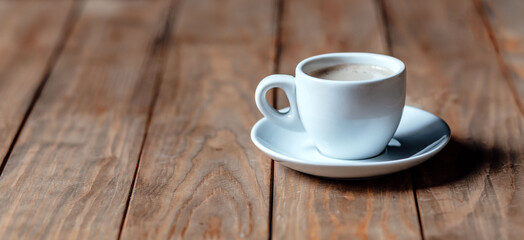 Cup of coffee on an old wooden table. White ceramic. Aromatic coffee with foam