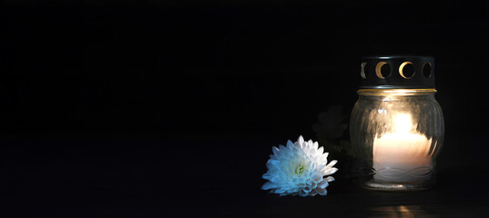 Votive candle lantern and flower on black background with copy space. Condolence card. All Saints...
