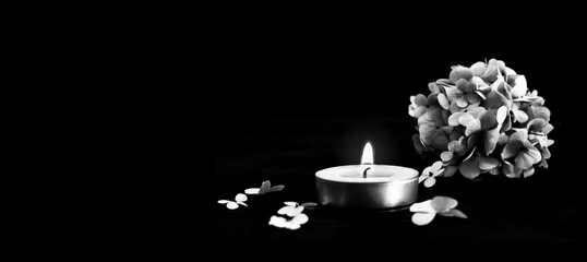 Condolence card with candle and  flowers isolated on black background with copy space 