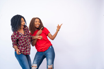 two beautiful young black women feeling excited and happy and pointing to the space to their side. an advertising concept