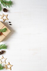 Christmas tree branches, cones and wooden Christmas accessories on a white wooden background.