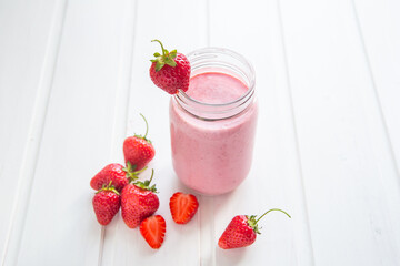 Fresh strawberry smoothie on a white wooden background.