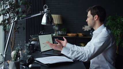 Businessman working with graphs on laptop in office. Worker looking at graphics