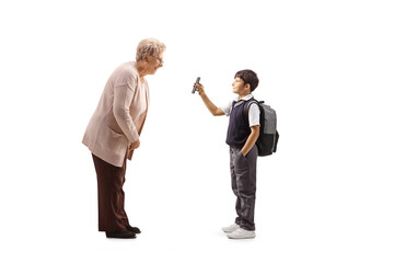 Schoolboy in a uniform standing and showing a smartphone to an older lady