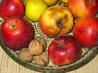 Rotten apples and walnuts on a crystal platter