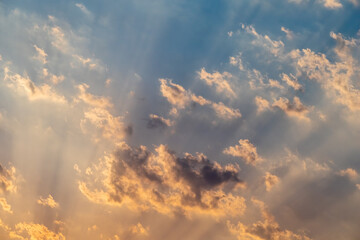 Fototapeta na wymiar Sun beams breaking through clouds in the blue sky