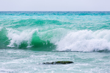 Amazing turquoise waves and white foam. Waves crashing on the coast of Lebanon. Blue sea water. A vibrant seascape for a holiday resort. Lebanese Mediterranean coastline
