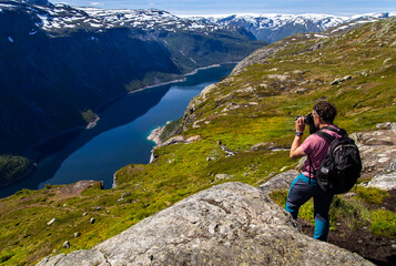 A photographer is taking pictures of Norwegian mountains and fjords. 