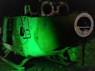 broken tail end of disused abandoned Helicopter grounded at night with lighting to show controls wiring and component parts 