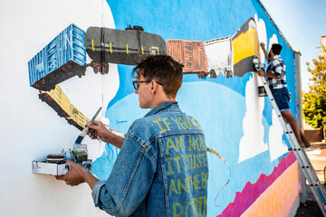 Artists Creating a Train Mural on the Side of a Building