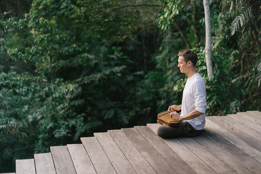 Man playing folk harp on terrace