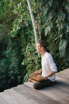 Man playing folk harp on terrace