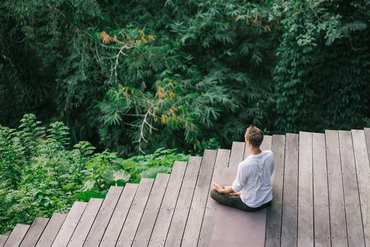Anonymous meditating on terrace in exotic woods