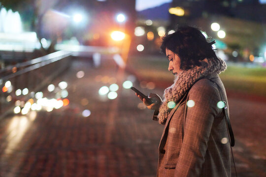 Double exposure of woman at traffic overpass at night, with phone