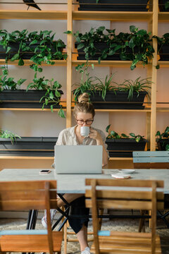 Woman spending time in a cafeteria with phone, coffee and books.