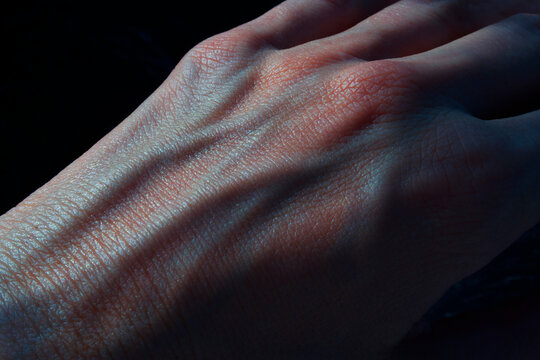 hand with blue blood veins in the dark closeup