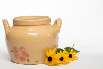 Antique crock with yellow flowers isolated on a white background
