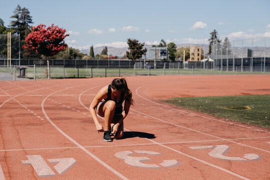 Woman Tying Her Shoe on the Running Track