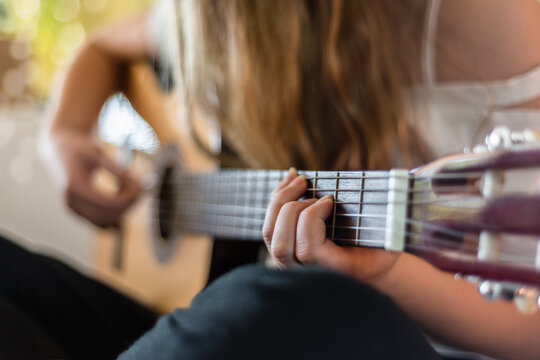 teen playing guitar in her bedroom