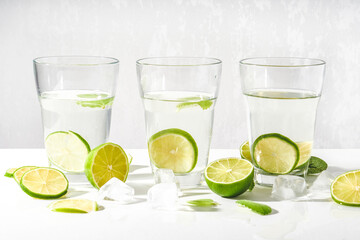 Fototapeta premium Drink glasses with water ,lime,mint and ice on white background